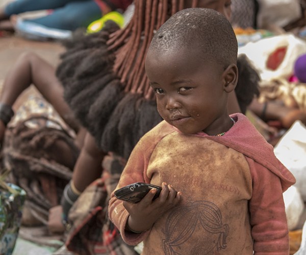 imagen niño himba en Namibia con móvil en la mano. El alcance de la tecnología.