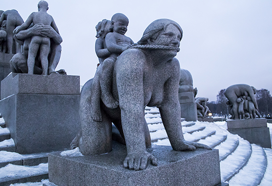 Detalle mujer jugando con dos niños en su espalda, las trenzas son las riendas. Obra en granito.