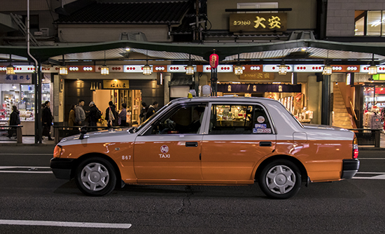 Taxi amarillo y techo blanco en calle de Kioto